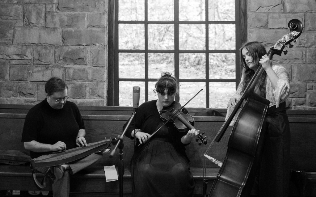 Black-and-white photo of Clay, Violet, and Anabel playing inside The Chapel at Pine Mountain Settlement School.